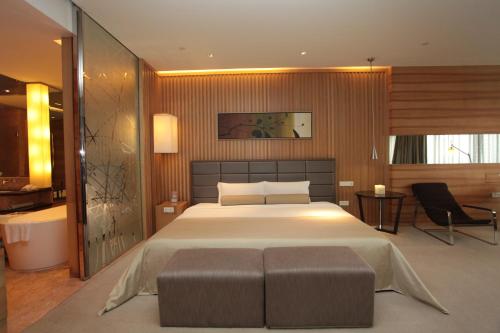 a bedroom with a large bed and a chair at HJ International Hotel in Dongguan