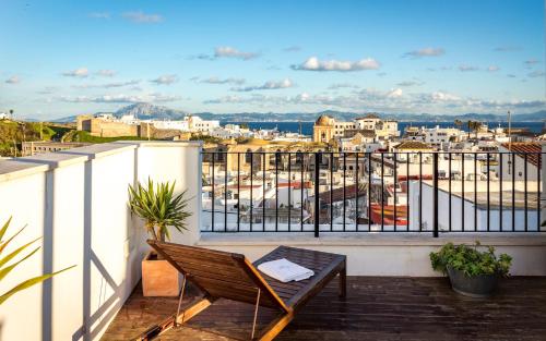 a chair on a balcony with a view of a city at Hotel Boutique Room Tarifa in Tarifa