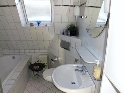 een badkamer met een wastafel, een toilet en een spiegel bij Ferienwohnung Emma in Leer