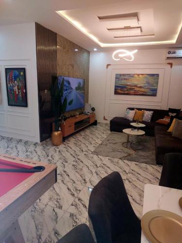 a living room with a couch and a tv at 3Bed Profssnal & Family Friendly with Swimming pool, Work Stns, PS5, Gym & near Beaches in Lagos