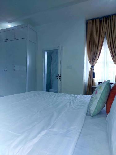 a large white bed in a room with a window at 3Bed Profssnal & Family Friendly with Swimming pool, Work Stns, PS5, Gym & near Beaches in Lagos