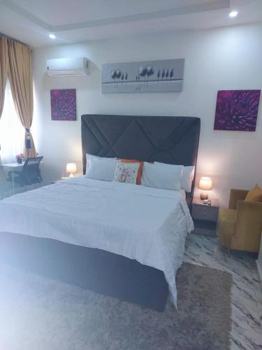 a bedroom with a large white bed and a chair at 3Bed Profssnal & Family Friendly with Swimming pool, Work Stns, PS5, Gym & near Beaches in Lagos