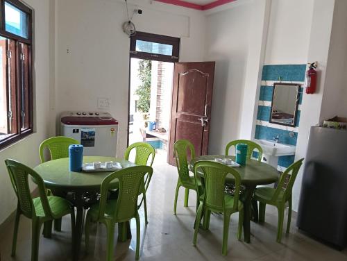 a room with two tables and green chairs and a kitchen at ganga palace in Munsyari