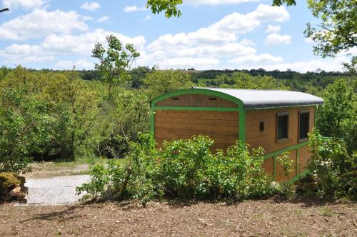 a small building with a green roof in a field at La Roulotte d'Alcas in Saint-Jean-et-Saint-Paul