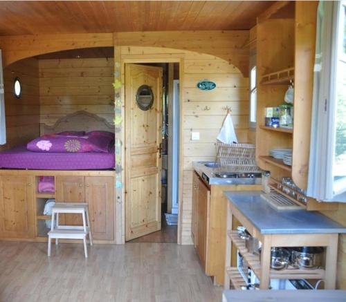 a log cabin kitchen with a purple bed in it at La Roulotte d'Alcas in Saint-Jean-et-Saint-Paul