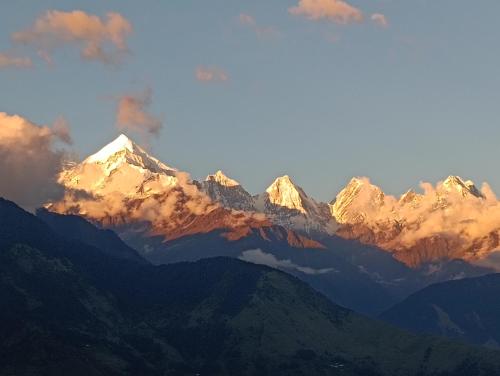 a view of a mountain range with clouds in the sky at ganga palace in Munsyari