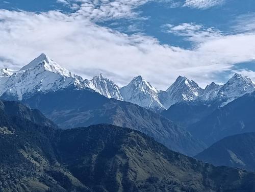 a view of a mountain range with snow capped mountains at ganga palace in Munsyari