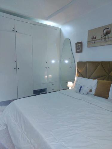 a bedroom with a large white bed and a large white cabinet at 3Bed Profssnal & Family Friendly with Swimming pool, Work Stns, PS5, Gym & near Beaches in Lagos