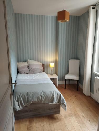 une chambre avec un lit et une chaise dedans dans l'établissement Appartement au cœur de Poitiers, à Poitiers