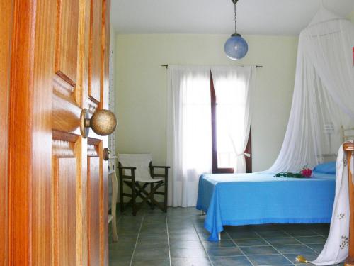 a bedroom with a blue bed and a window at Alkyon Villas in Sivota