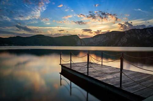 a dock on a body of water with a sunset at Vila Golful Dunării in Dubova