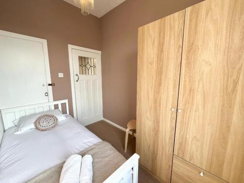 a bedroom with a white bed and a wooden cabinet at Cosy 4 bedroom house in Marshside