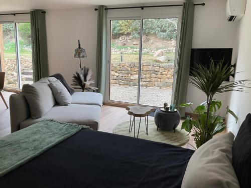 a living room with a bed and a couch and window at Villa La Liberté in Arles-sur-Tech