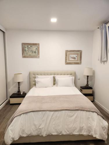 a white bedroom with a large bed with two lamps at Santa Beatriz Apartment in Machico