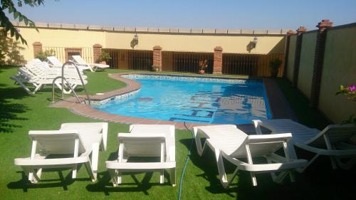 a group of white chairs and a swimming pool at Alojamiento Nohal in La Iruela