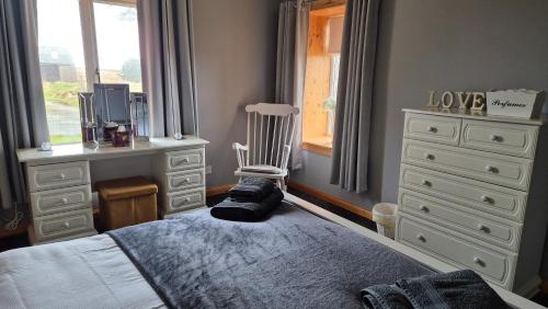 a bedroom with a bed and a chair and a dresser at Mackenzie 25 in Stornoway