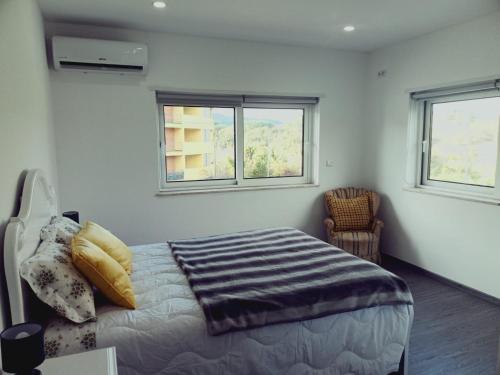 a bedroom with a bed and two windows at Casa da Angelina in Ponte da Barca