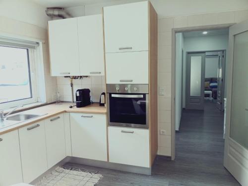 a kitchen with white cabinets and a microwave at Casa da Angelina in Ponte da Barca