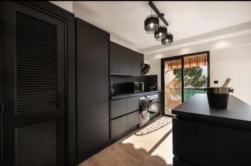 une cuisine avec des armoires noires et un comptoir noir dans l'établissement Appartement haut standing - Luxury apartment - Cannes- Croisette- Centre ville- Vue Tennis -Vue Piscine -Parking privé - Terrasse- Plage, à Cannes