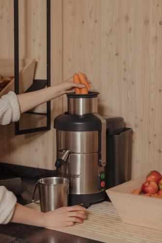 a woman is using a coffee maker in a kitchen at Hotel Marten - Ski-In & Ski-Out in Saalbach Hinterglemm