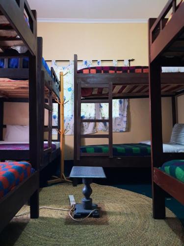 a room with three bunk beds and a table in it at Ibrahim Garden Hostel in Arusha
