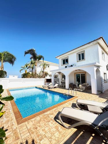 a swimming pool in front of a house at Hephaestus Family Villa, Ayia Triada Beach in Paralimni