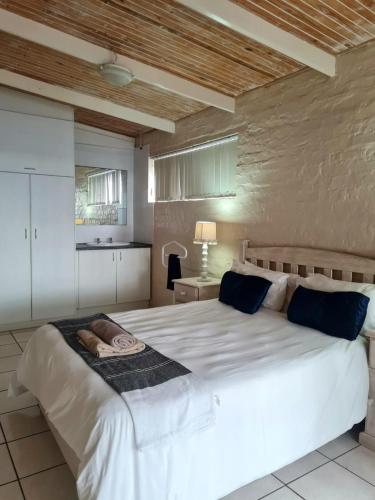 Un dormitorio con una gran cama blanca con almohadas azules. en Point Village Accommodation - Snowdove, en Mossel Bay
