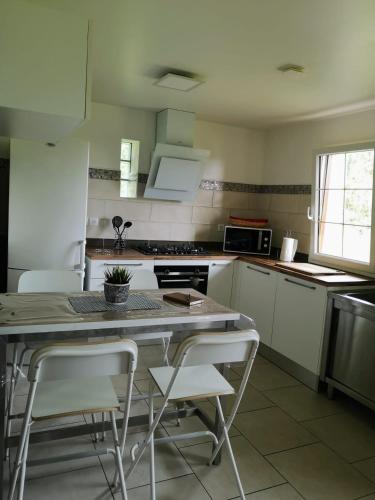 une cuisine avec des armoires blanches et une table et des chaises dans l'établissement Chambre Nature, à Saint-Justin