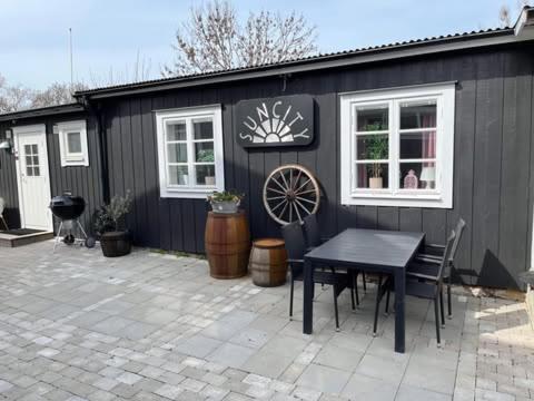 a black shed with a table and chairs in front of it at Suncity Solsidan in Borgholm