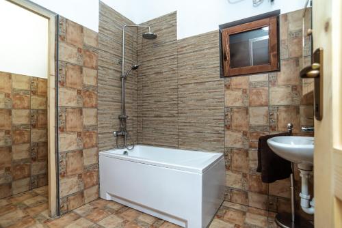a bathroom with a white tub and a sink at Adlin in Homokcsárda