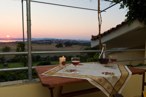 a table with two glasses of wine on a balcony at Villa Panorama in Moúdhros