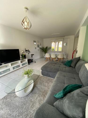 un salon avec un canapé et une télévision à écran plat dans l'établissement Maison 100m2 avec jardin aux portes de Caen, à Hubert-Folie