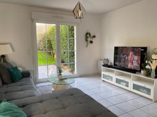un salon avec un canapé et une télévision dans l'établissement Maison 100m2 avec jardin aux portes de Caen, à Hubert-Folie
