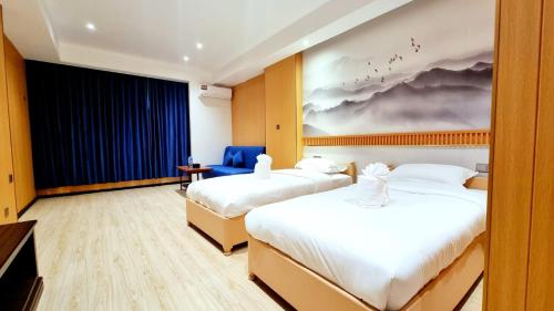 サワンナケートにあるHoongthip hotelのベッドが2つあり、壁に絵が飾られたホテルの部屋