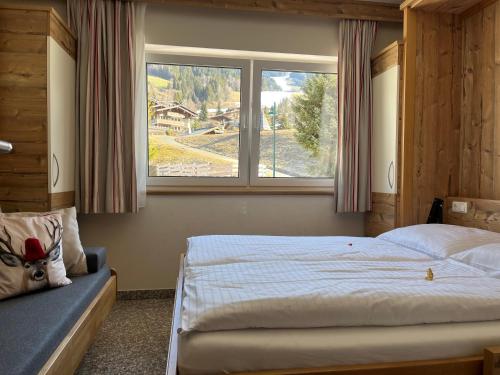 a bedroom with a large bed and a window at Boutique Apartment BERGLIEBE, ski in-out in Saalbach Hinterglemm