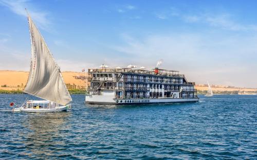 a large boat and a sailboat on the water at Movenpick SS Misr Steamer Nile Cruise - 04 & 07 Nights Each Monday From Luxor and 03 Nights Each Friday from Aswan in Luxor