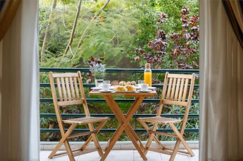 a table with two chairs and a breakfast on a balcony at Madeira Funchal Gardens in Funchal