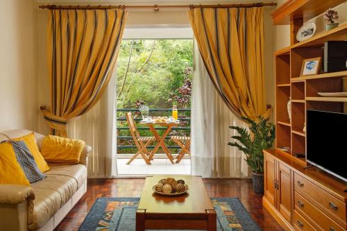 a living room with a couch and a large window at Madeira Funchal Gardens in Funchal