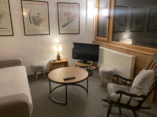 un salon avec une télévision, une table et des chaises dans l'établissement Appartement 4 pièces - 8 personnes - Résidence le France, à La Plagne Tarentaise
