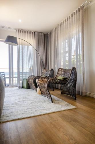 a living room with wicker chairs and a large window at Beach Villa Wilderness in Wilderness