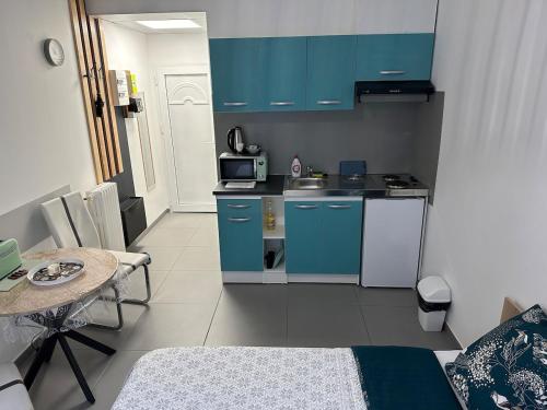 une petite cuisine avec des placards bleus et une table dans l'établissement Studio ElevenStar, à Aubervilliers