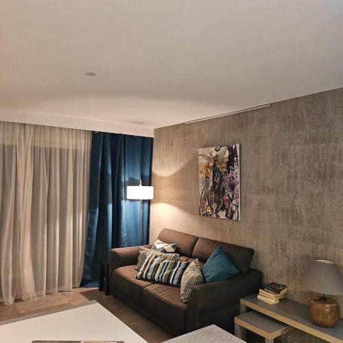 - un salon avec un canapé brun et des rideaux bleus dans l'établissement Appartement les pieds dans l'eau avec terrasse et jardin, à Bandol