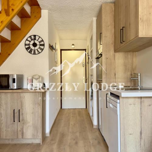 a kitchen with wooden cabinets and a clock on the wall at Grizzly Lodge - appartement duplex sur les pistes in Les Gets
