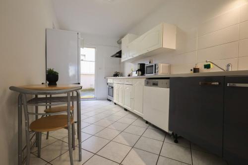 une cuisine avec des armoires blanches et une table à l'intérieur dans l'établissement L'émeraude, à Loyettes