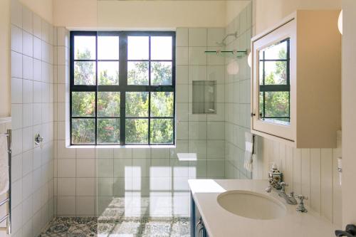 a white bathroom with a sink and a window at Stanford Riverside Retreat - Hotub & Pool in Stanford