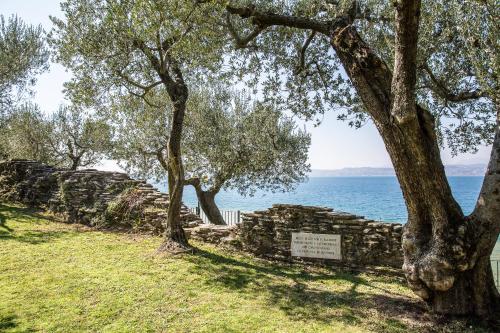 a stone wall and trees next to the water at Hotel Ideal in Sirmione