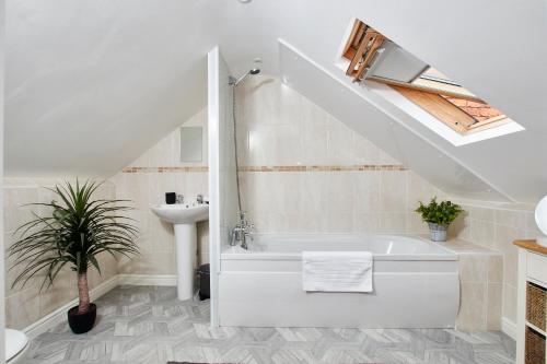 a bathroom with a bath tub and a sink at Delven House- Serviced Apartments in Castle Donington
