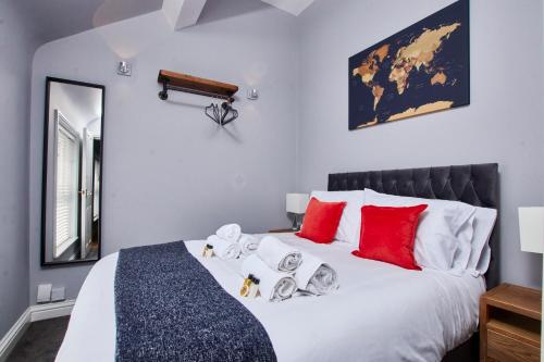 a bedroom with a large white bed with red pillows at Delven House- Serviced Apartments in Castle Donington