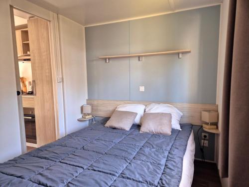 - une chambre avec un lit bleu et 2 oreillers dans l'établissement MH 467 Isalisa 3chambres et 1 salle de bain dans camping 4 étoiles avec PARC AQUATIQUE, à Saint-Julien-en-Born