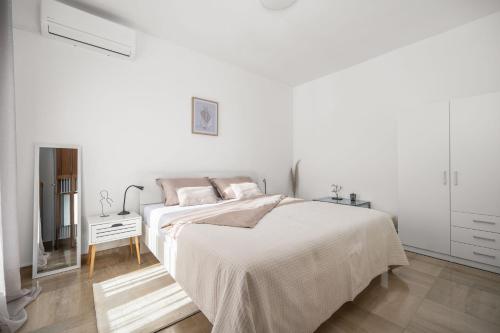 a white bedroom with a bed and a television at Blue Horizon Apartment a Seaside Escape in Rabac in Rabac